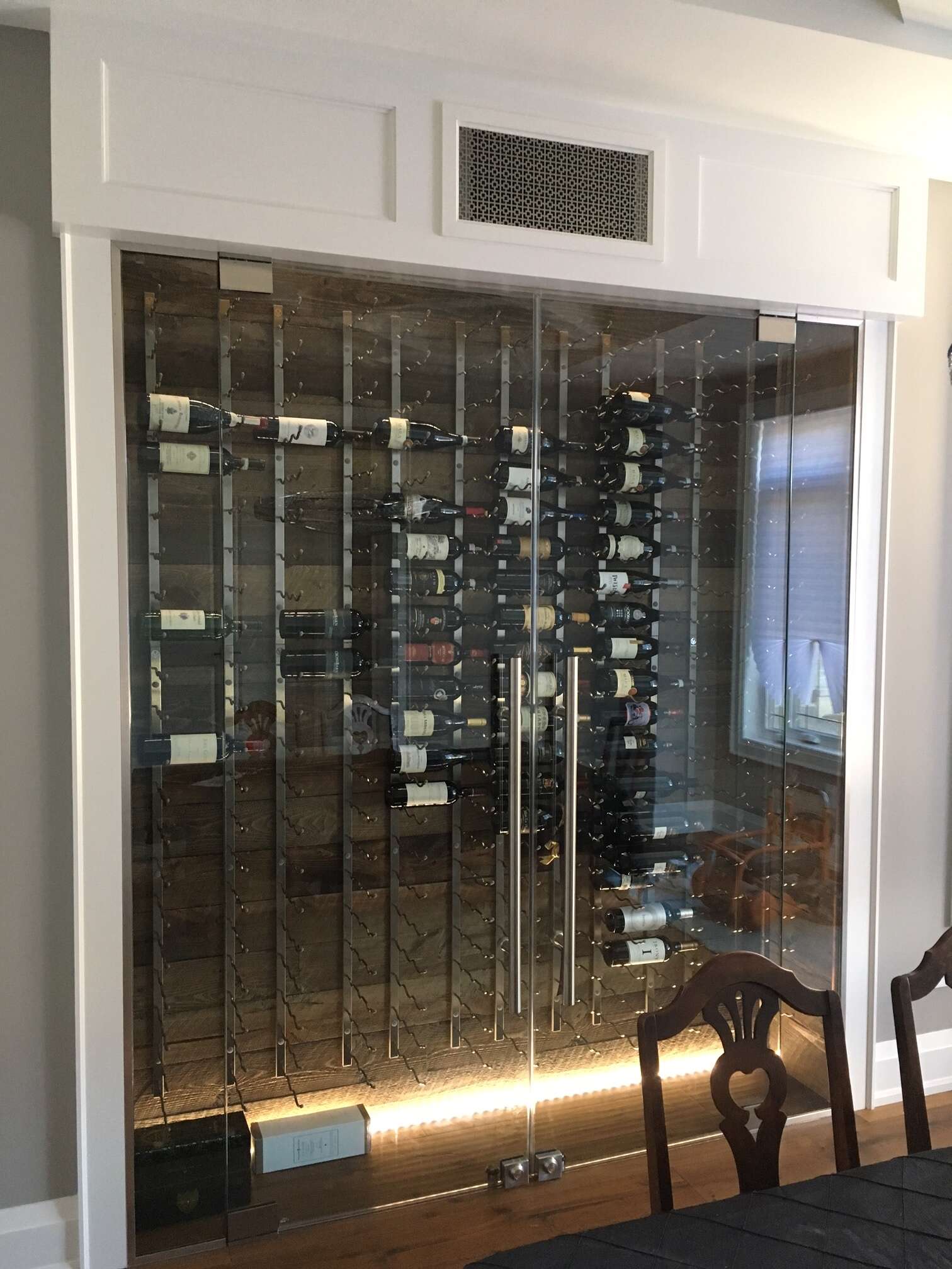 Conditioned custom wine enclosure featuring VV racking, double tempered glass doors and custom register.