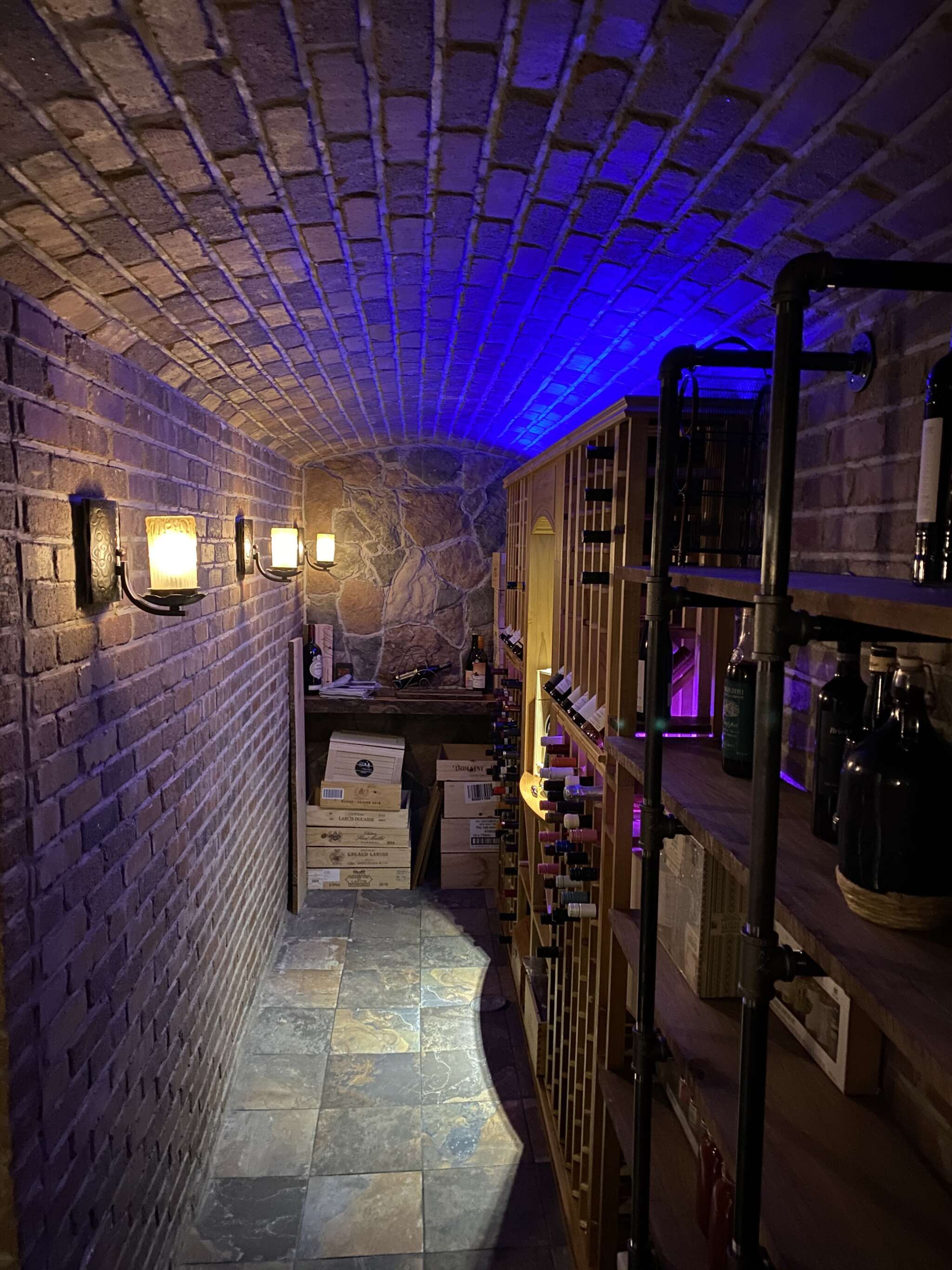 Custom cantina wine cellar featuring LVG racking, custom stonework and lighting.